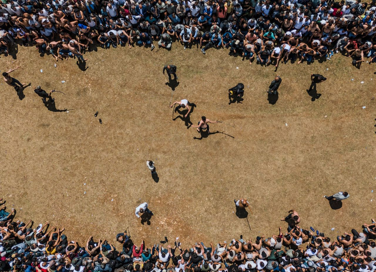 Services Aerial view of a large crowd surrounding an open field event with spectators watching closely.